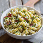 Protein pasta salad in white bowl on rustic table