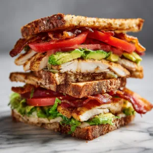 Healthy chicken club sandwich with bacon and avocado on toasted whole grain bread.