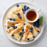 Blueberry breakfast quesadilla sliced and served with honey and fresh berries.